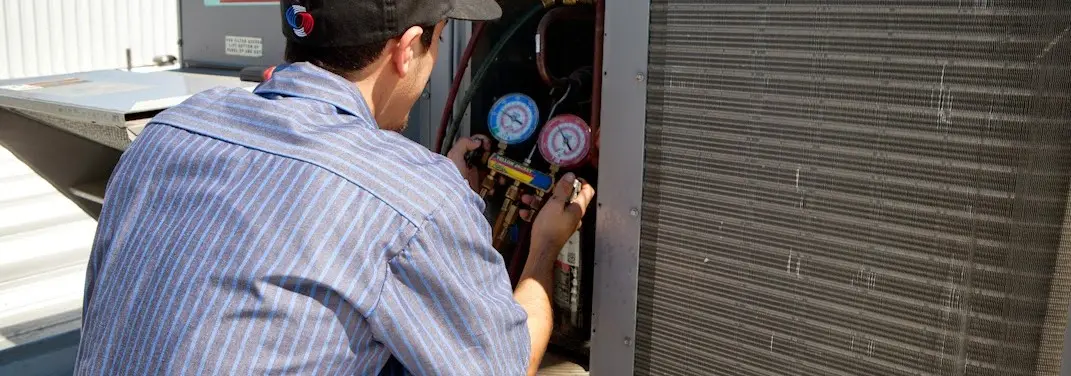 HVAC technician servicing a condenser unit in Standish